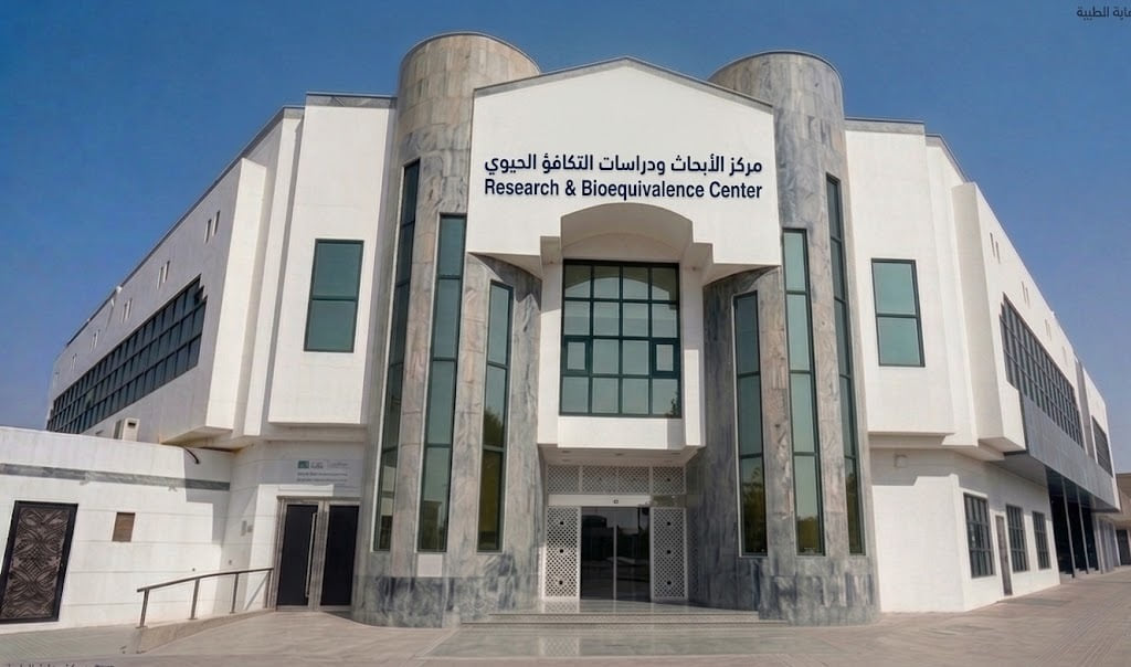 The building housing NAMA Bio-Center, a white stone and green-marble facade carrying CARE Medical branding and signage reading Research & Bioequivalence Center in Arabic and English.
